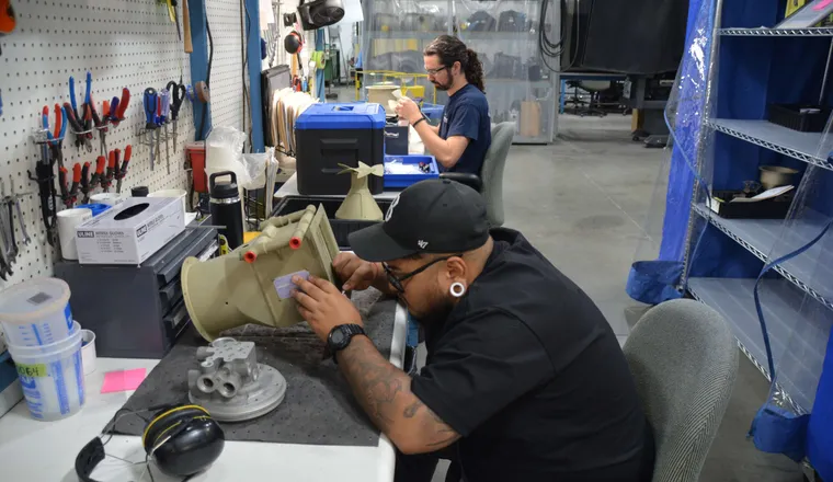 Two QTC technicians overhauling aircraft components at the workbench